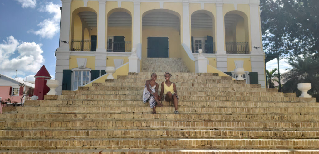 Image of Kayla Harley and Charlita Shuster sitting on the stairs of the Government House in St. Croix